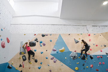 Two women climbing on the wall in climbing gym