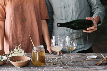 Midsection of man pouring wine in glass while preparing cocktail with girlfriend