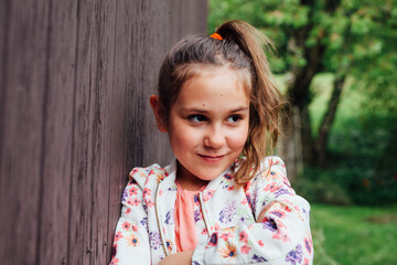 Portrait of smiling girl leaning against wooden wall