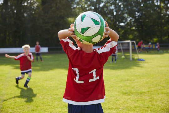 Soccer boy throwing ball on field - Powered by Adobe