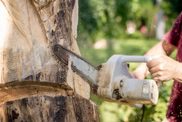 Wood carver carving sculpture, using chainsaw