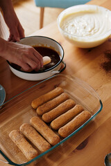 Woman's hand dipping ladyfingers in coffee