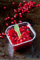 Pomegranate seed and plastic spoon in plastic box