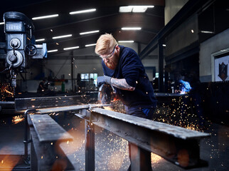 Welder using circular grinder while working at factory