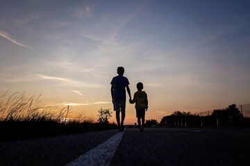 Two boys, brothers, children, blond boys with pet dog, maltese breed, walking on a road in rural,...