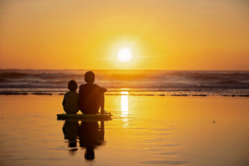 Happy children, boys, playing on the beach on sunset, kid cover in sand, smiling, laughing