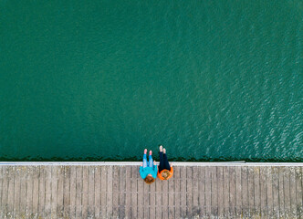 Two friends sitting side by side on jetty, Valdemurio Reservoir, Asturias, Spain