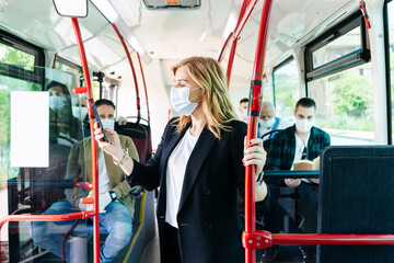 Businesswoman wearing protective mask in public bus looking at cell phone, Spain