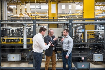Three men talking in factory shop floor