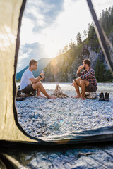 Germany, Bavaria, two hikers camping on gravel bank in the evening