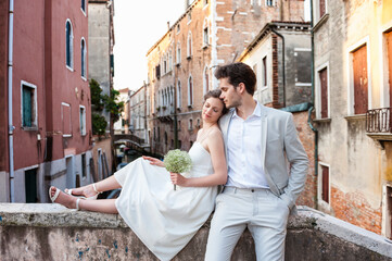 Italy, Venice, bridal couple on little bridge in the morning