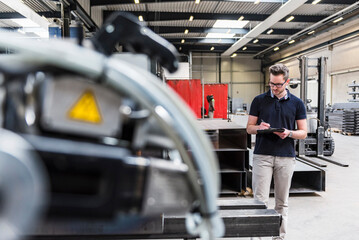 Man writing on clipboard on factory shop floor