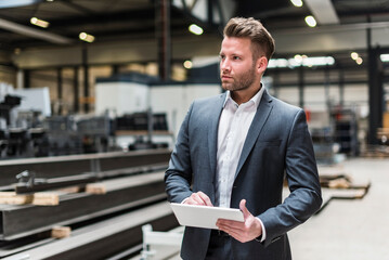 Businessman using tablet on factory shop floor