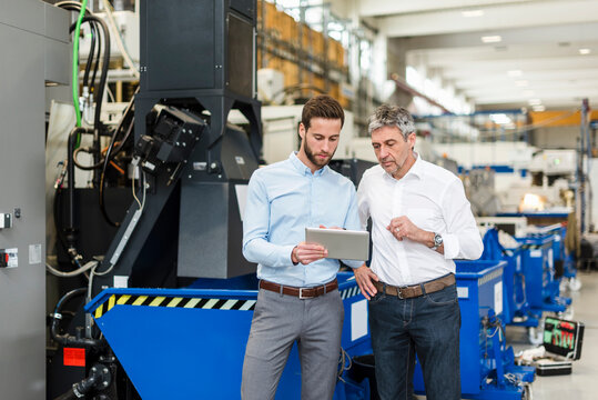 Businessmen using tablet during meeting in production hall