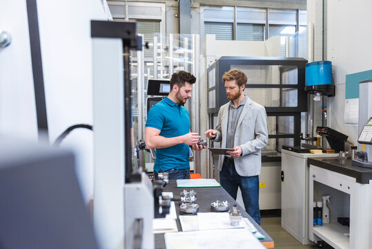 Two men with tablet talking in modern factory