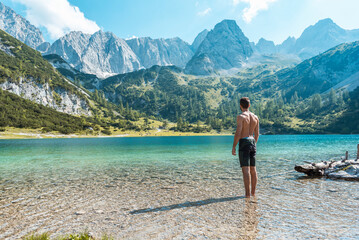 Austria, Tyrol, Young man at Lake Seebensee standing ankle deep in water