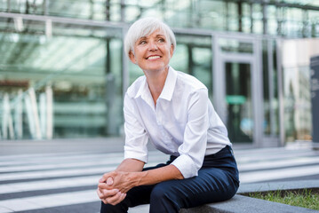 Smiling senior businesswoman sitting outside looking around