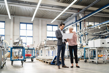 Businessman and senior woman looking at plan in a factory