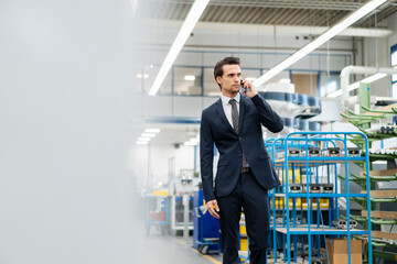 Businessman on cell phone in a factory