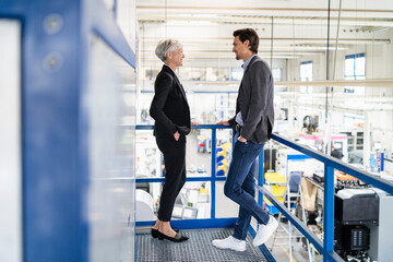Smiling businessman and senior businesswoman talking in a factory