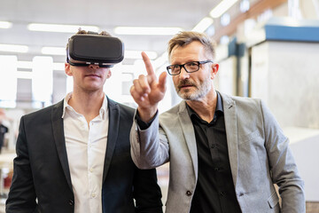 Two businessmen with VR glasses in factory