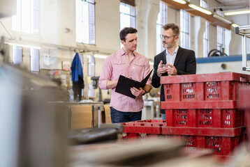Two men in factory examining workpiece