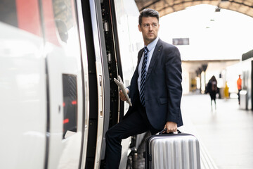 Businessman with suitcase getting in train