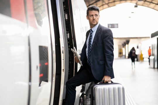 Businessman with suitcase getting in train