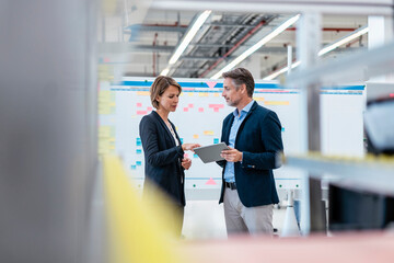 Businessman and businesswoman talking in a factory hall