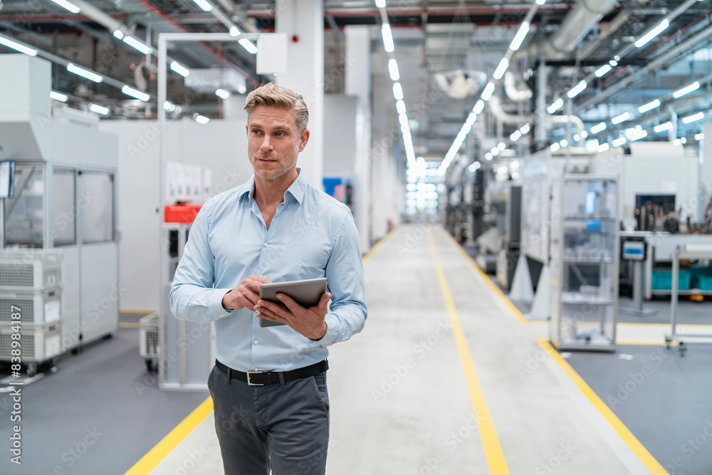 Poster Businessman using tablet in a modern factory