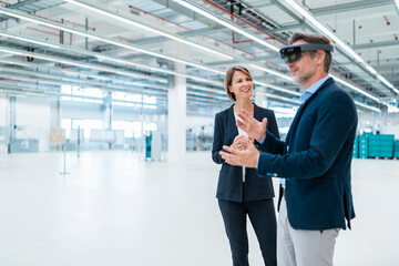 Businessman with AR glasses and businesswoman in a factory hall
