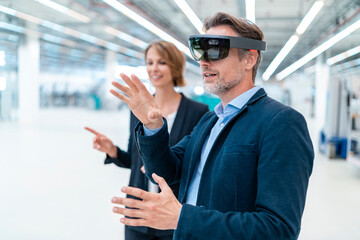 Businessman with AR glasses and businesswoman in a factory hall