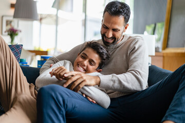 Father and son having fun on couch in living room