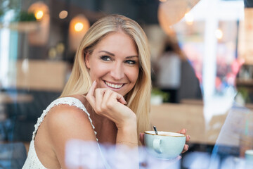 Portrait of smiling blond woman drinking coffee in a cafe