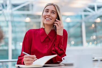 Smiling young businesswoman with notebook on the phone