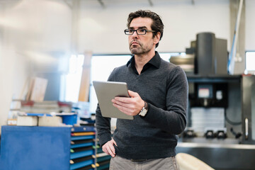 Businessman holding tablet in a factory