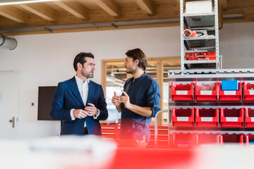 Businessman and employee talking in factory