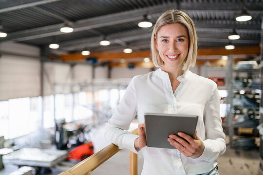 Portrait of smiling young woman using tablet in a factory