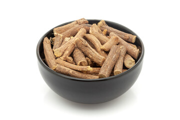Close-up of Dry Organic Liquorice or Mulethi (Glycyrrhiza glabra), in black ceramic bowl. Isolated on a white background.