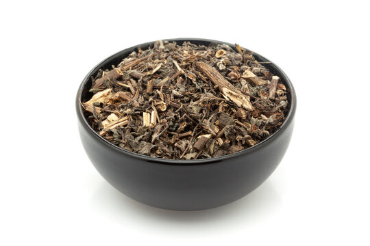 Close-up of Dry Organic Bhringraj (Eclipta prostrata) leaves, in black ceramic bowl. Isolated on a white background.