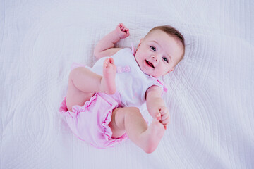 Baby girl touching toes while lying on blanket
