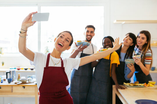 Playful instructor taking a selfie with friends in a cooking workshop