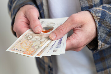 male hands holding money, counting English pound sterling bills, rejoices in success, anticipates...