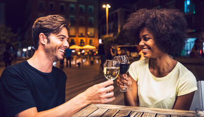 Cheerful couple looking at each other while toasting wineglasses at date night