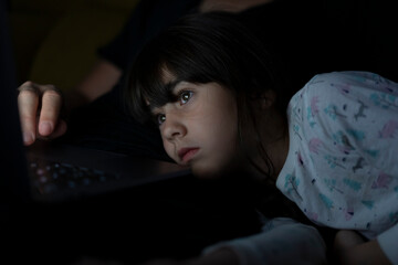 Portrait of daughter watching father using laptop on couch at night