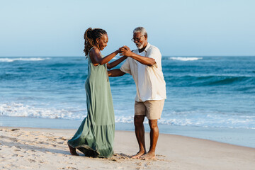 Mature African American couple dancing joyfully on beach