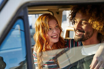 Smiling young woman looking at boyfriend in a car