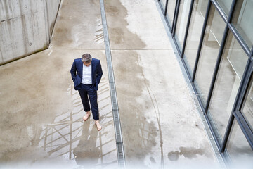 Barefoot businessman standing in a puddle