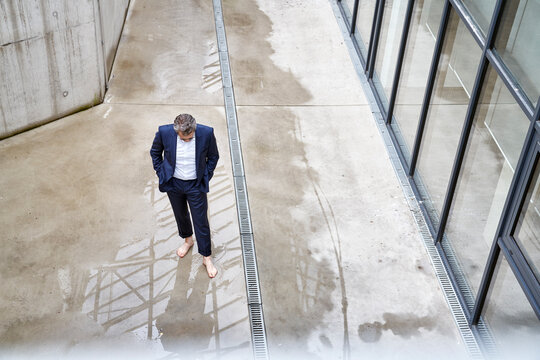 Barefoot businessman standing in a puddle - Powered by Adobe