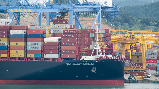 Busan, South Korea - 10.01.2023: ZIM Forward part of Mound Denali LNG fuel powered vessel has cargo operations in container terminal of port New Busan in stead of living buildings of Busan city 